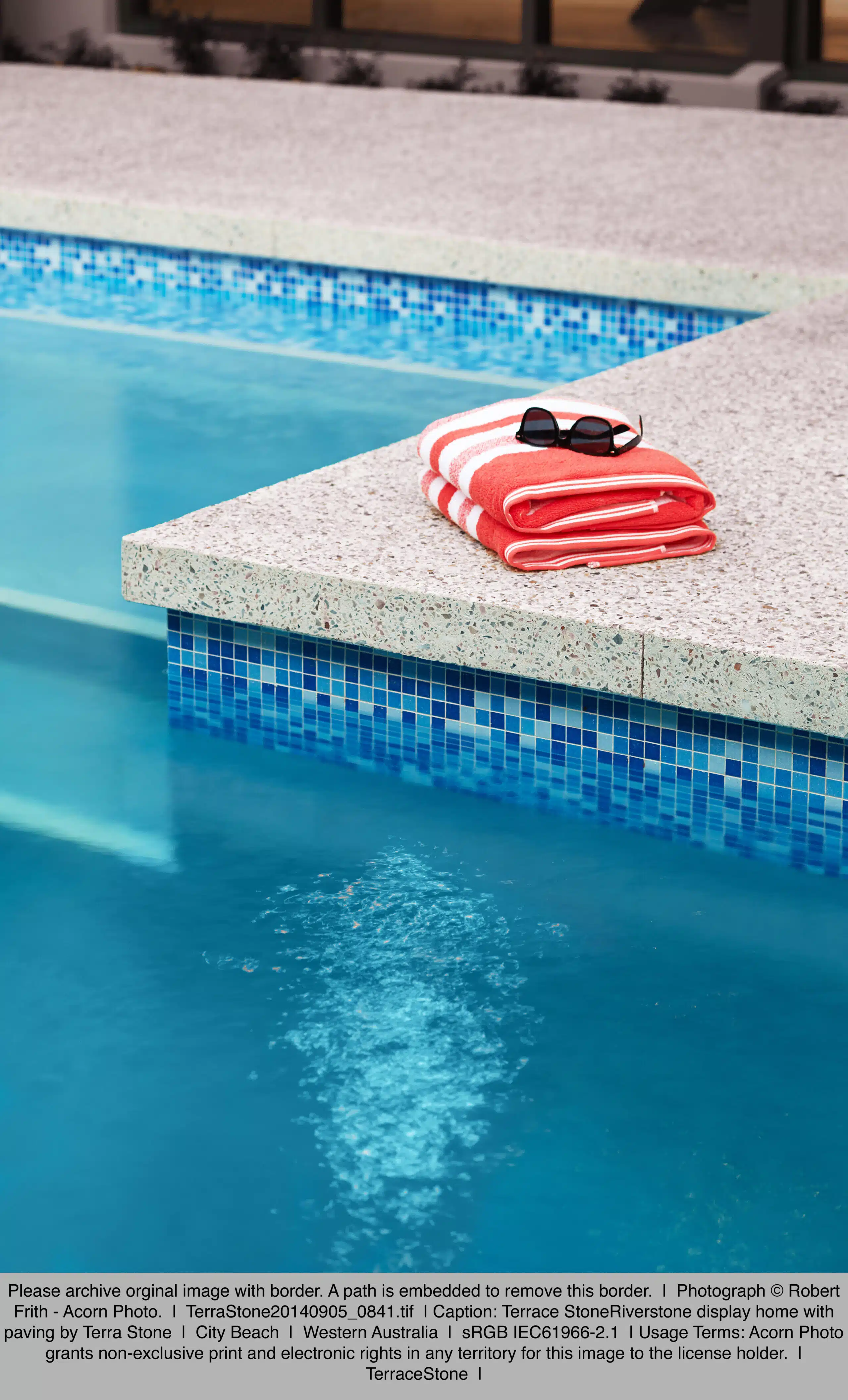 a neatly folded beach towel and sunglasses resting on the edge of a pool